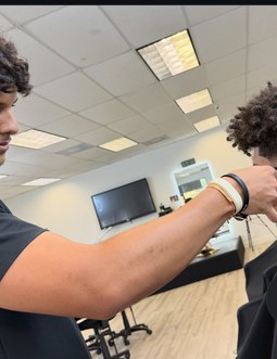 Student cutting a client's hair in class