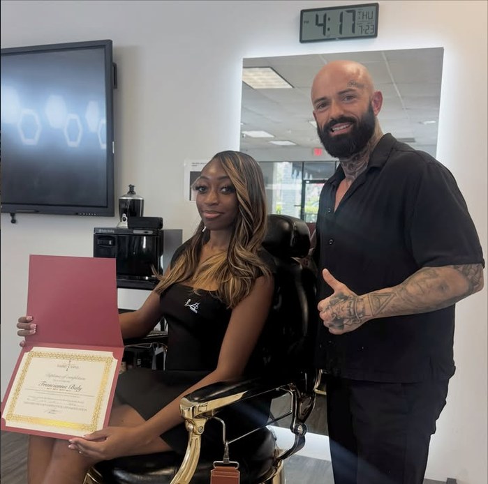 Director Tosh Juneau with a Signature Barber Academy graduate holding her diploma